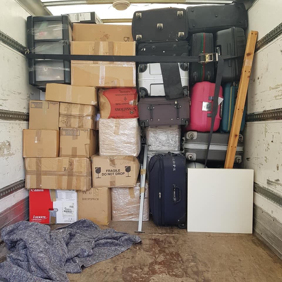 A moving truck filled with various luggage and boxes stacked in the back